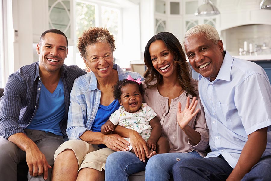 Personal Insurance - Parents, Baby Girl, and Grandparents on a Couch Together in a Beautiful Living Room